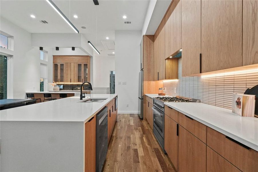 Kitchen featuring backsplash, appliances with stainless steel finishes, light hardwood / wood-style floors, sink, and a spacious island