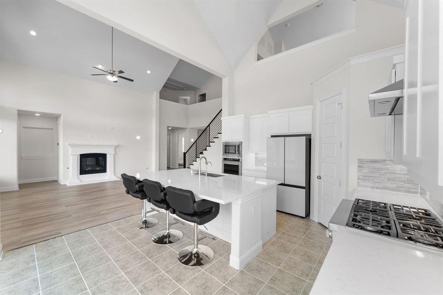 Kitchen featuring white cabinetry, appliances with stainless steel finishes, light hardwood / wood-style floors, tasteful backsplash, and ceiling fan