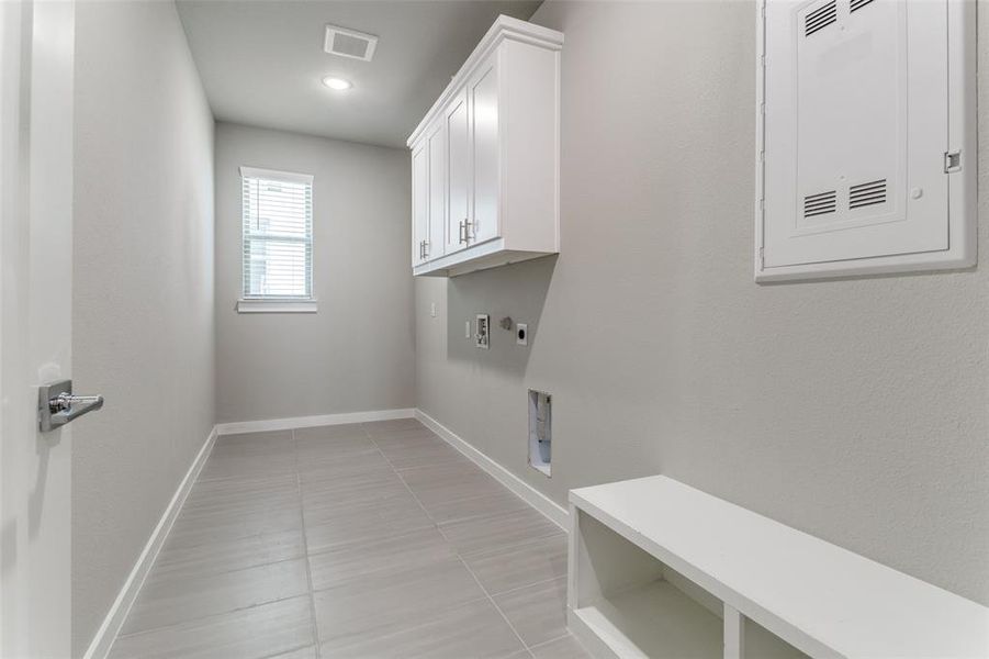 Washroom with cabinets, light tile patterned flooring, hookup for a washing machine, and hookup for an electric dryer