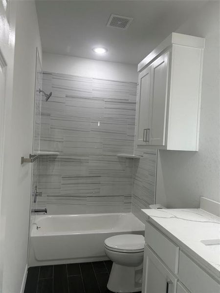 Full bathroom featuring tiled shower / bath, vanity, toilet, and tile patterned flooring