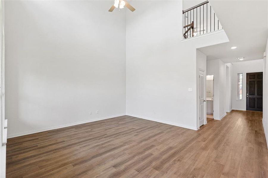 Spare room with a towering ceiling, wood-type flooring, and ceiling fan