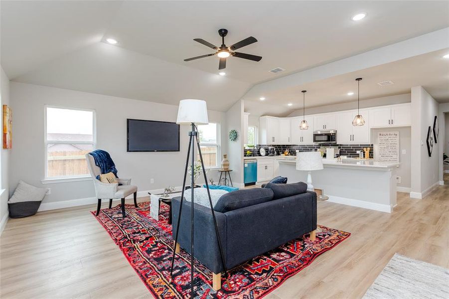 Living room with a wealth of natural light, vaulted ceiling, and light wood-type flooring