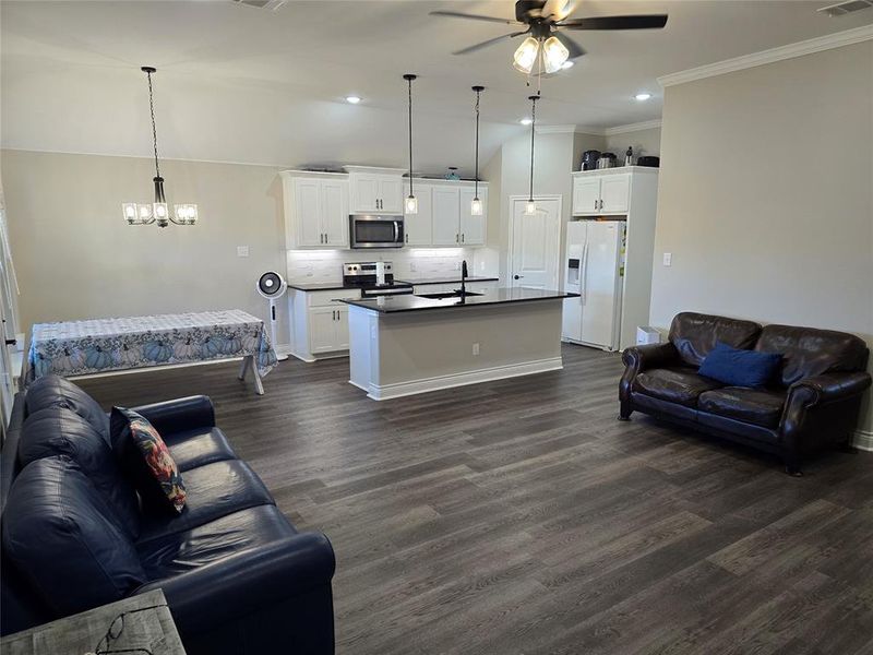 Living room with sink, ceiling fan with notable chandelier, crown molding, and dark hardwood / wood-style flooring