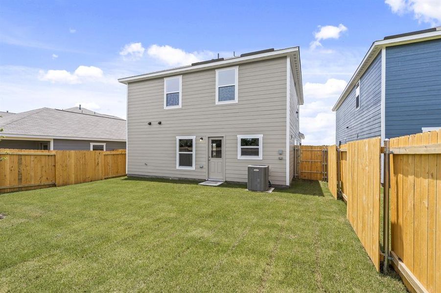 Back of property featuring central AC and a yard