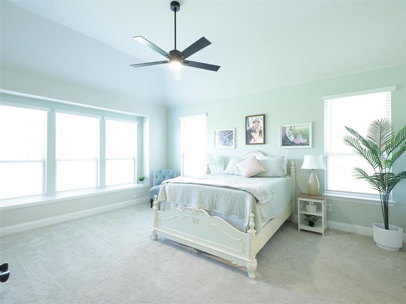 Bedroom with multiple windows, vaulted ceiling, ceiling fan, and light colored carpet