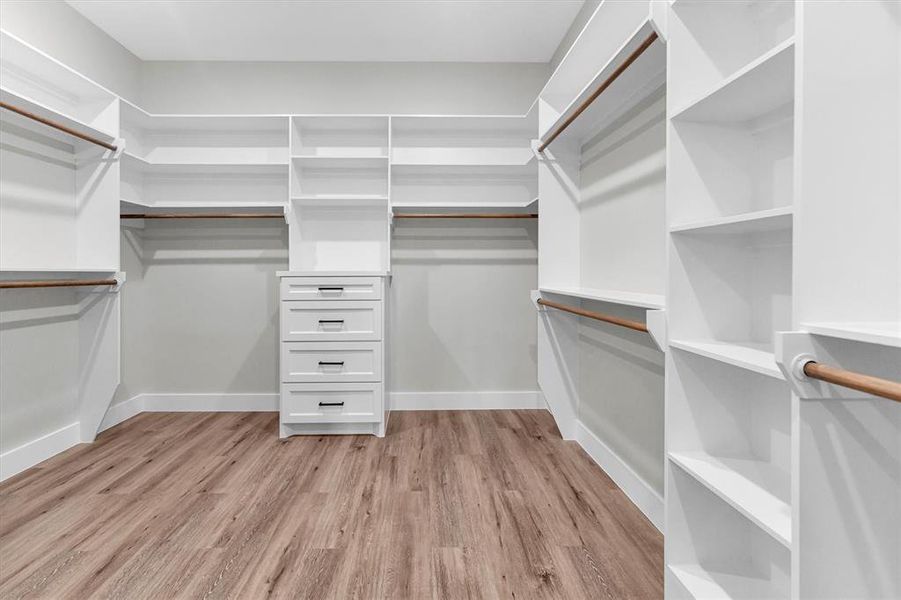 Large primary closet with abundant built-in shelving