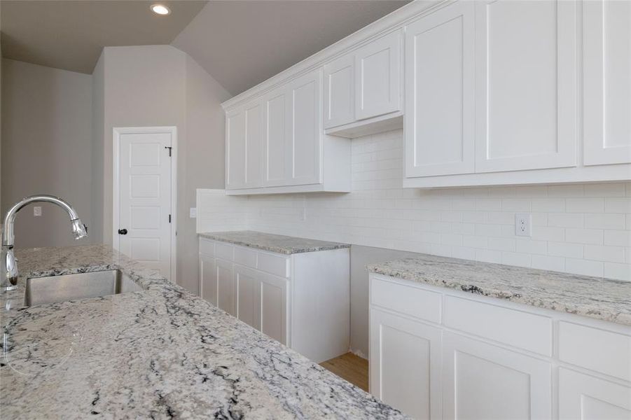 Kitchen with sink, white cabinetry, wood-type flooring, and decorative backsplash