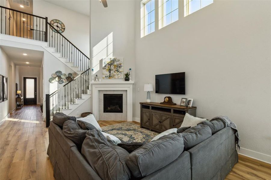 Living room featuring wood-type flooring, a towering ceiling and iron spindle staircase to the upstairs.