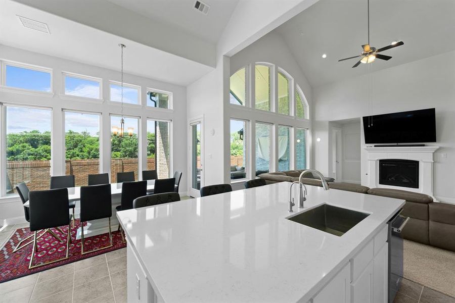 Kitchen featuring high vaulted ceiling, sink, white cabinetry, and a center island with sink