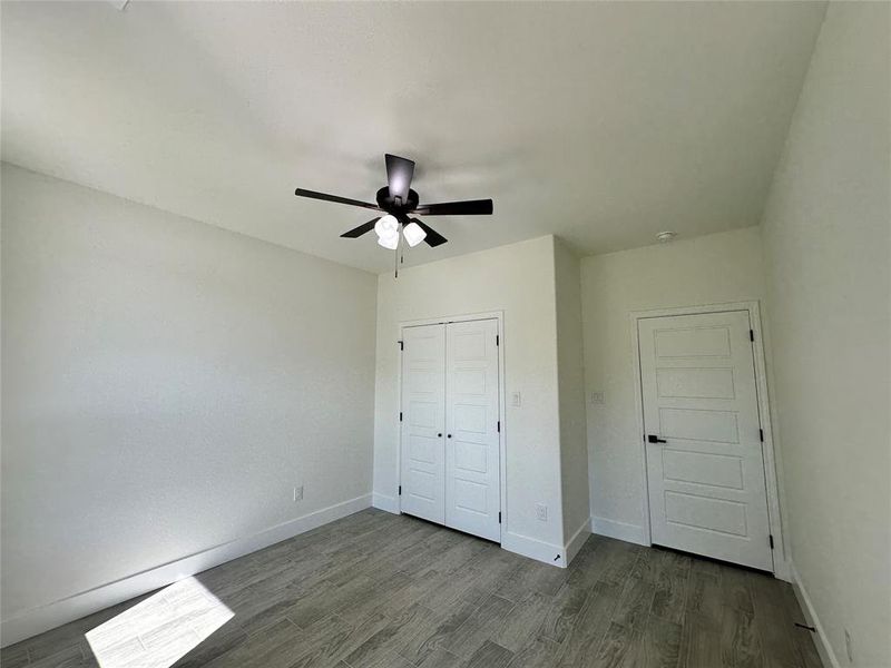 Unfurnished bedroom featuring ceiling fan, a closet, and hardwood / wood-style floors