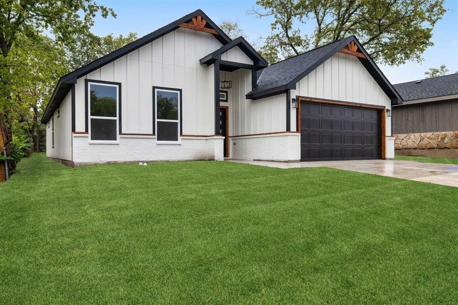 Modern inspired farmhouse with a garage and a front lawn