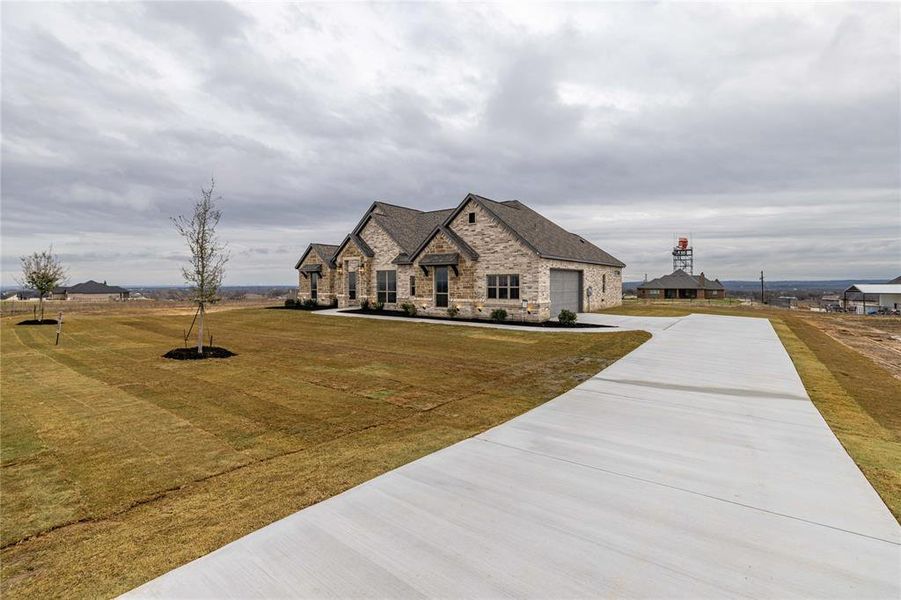 French country inspired facade featuring a garage and a front lawn