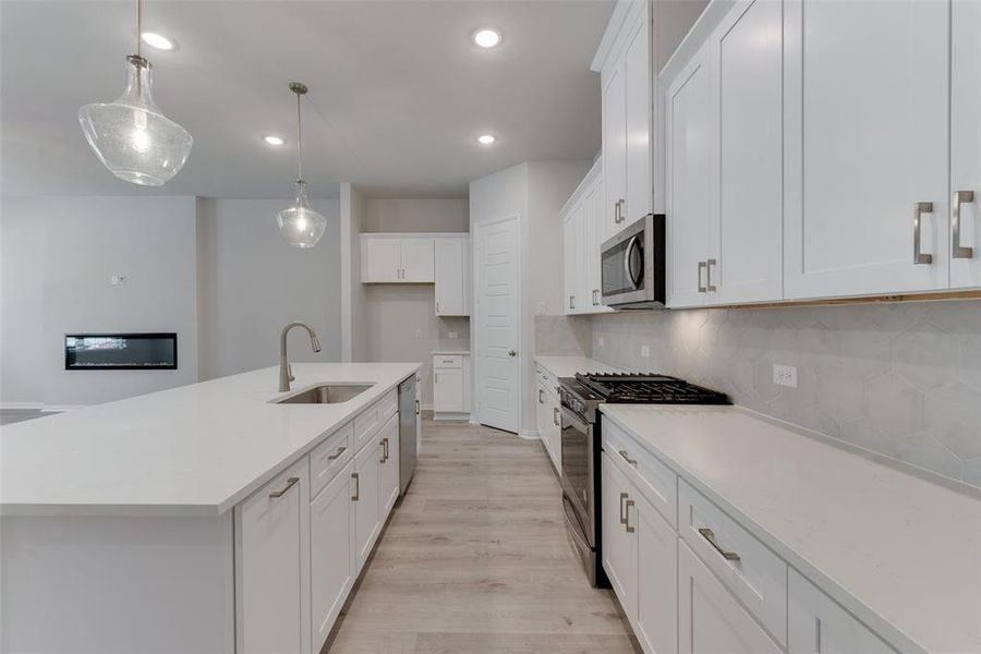 Kitchen with sink, appliances with stainless steel finishes, light hardwood / wood-style flooring, and white cabinets