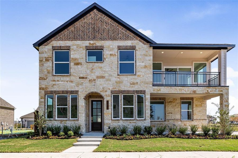 View of front facade featuring beautiful stone, a front yard and a balcony