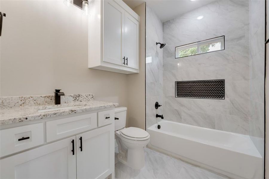 Full bathroom with tile floors, vanity, toilet, and tiled shower / bath combo