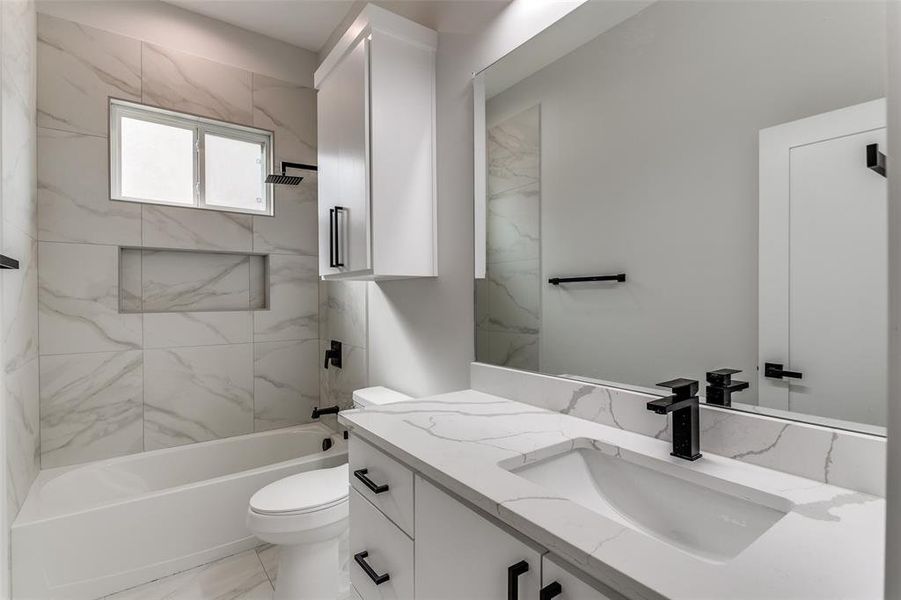 Full bathroom with tile floors, tiled shower / bath, oversized vanity, and toilet