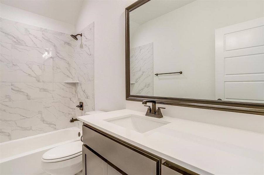 Full bathroom with tiled shower / bath, vanity, and toilet