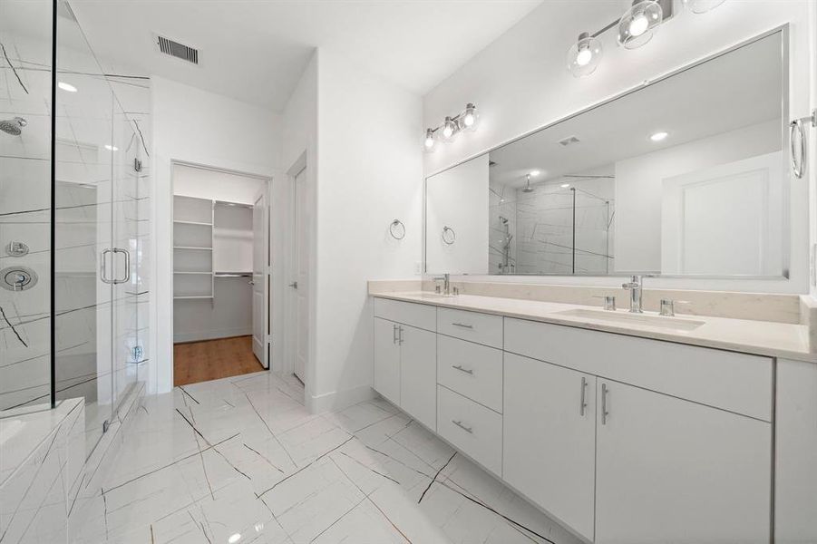 Riverway uses beautiful designer finishes in this large primary bathroom. It has a large glass shower, double sinks, and a soaking tub.