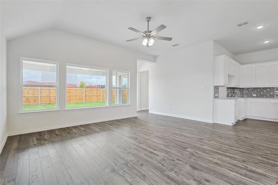 Unfurnished living room with ceiling fan, lofted ceiling, and dark hardwood / wood-style floors