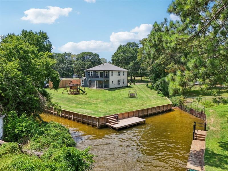 View of dock featuring a yard, a water view, and a playground