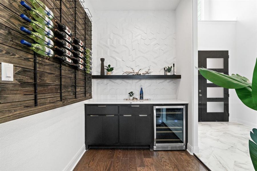 Inside the custom wine room featuring wine fridge, custom accent wall and floor to ceiling glass walls