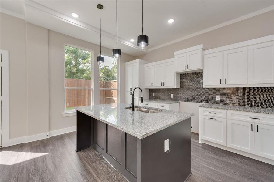 Kitchen featuring backsplash, white cabinetry, dark wood-type flooring, sink, and pendant lighting