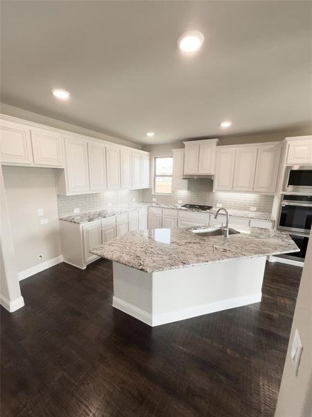 Kitchen with white cabinetry and a center island with sink