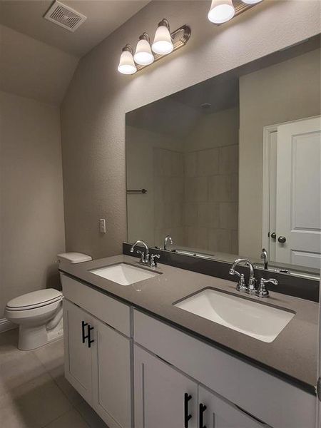 Bathroom with tile patterned floors, vaulted ceiling, toilet, and vanity