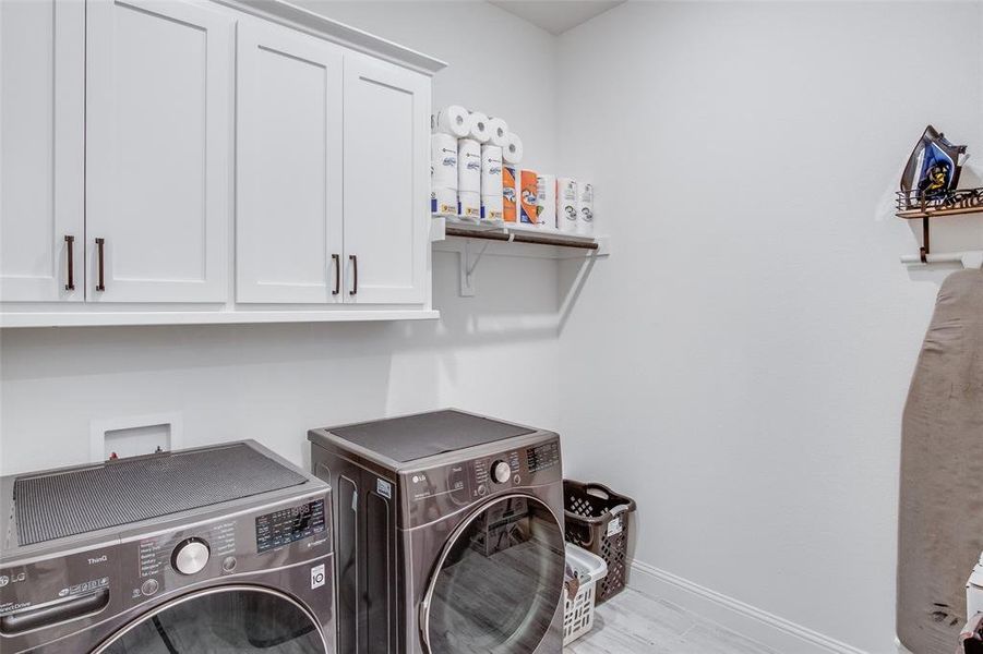 Laundry area featuring washer and dryer, cabinets, washer hookup, and light hardwood / wood-style flooring