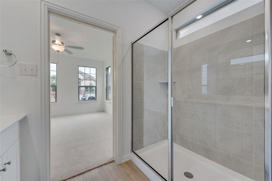 Bathroom featuring walk in shower, hardwood / wood-style floors, vanity, and ceiling fan