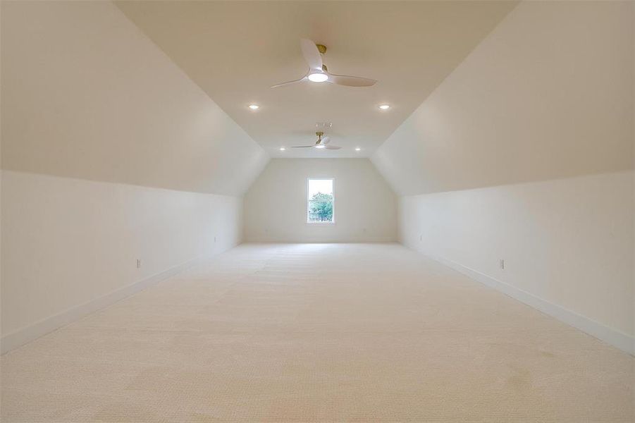 Bonus room featuring lofted ceiling, light colored carpet, and ceiling fan