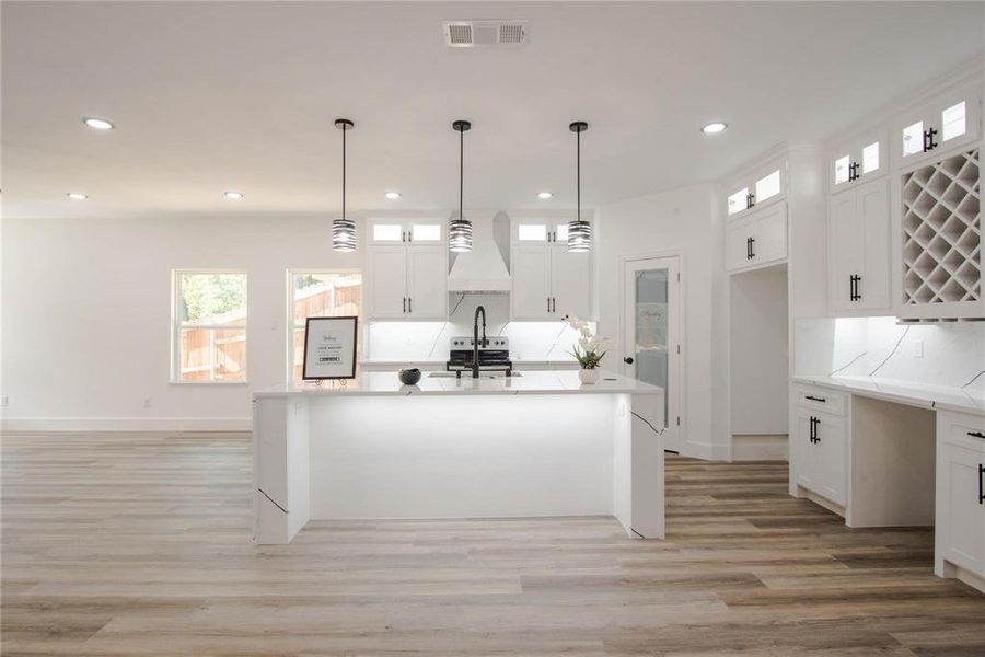 Kitchen with white cabinets, hanging light fixtures, and light hardwood / wood-style flooring