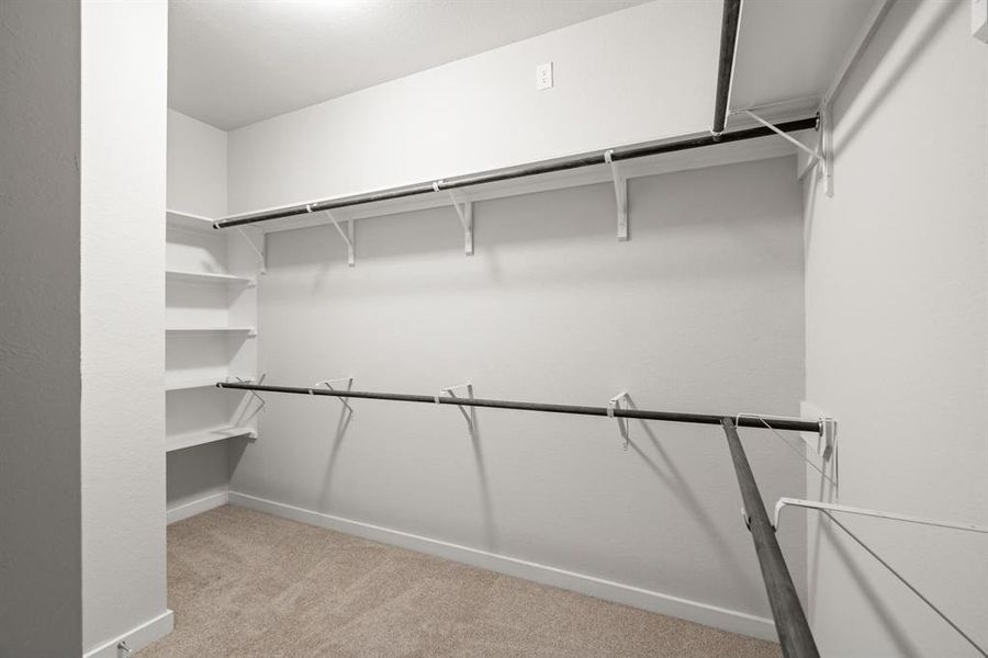 Walk-in closet that epitomizes luxury and practicality. This generously sized space features built-in shelving, offering abundant room for impeccable organization. Sample photo of completed home with similar floor plan. As-built interior colors and selections may vary.