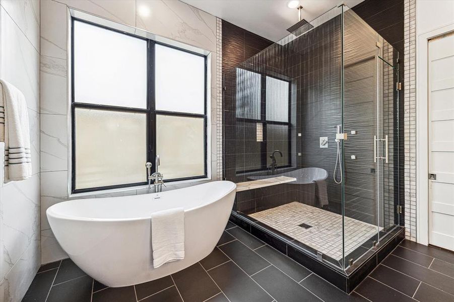 Check out the stunning tile that extends all the way up to the ceilings! Enjoy a luxurious soaker tub and a walk-in shower equipped with a bench, rainhead, and handheld fixtures. Everyday is a day at the spa