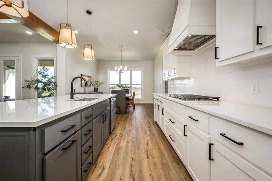 Kitchen featuring white cabinets, sink, light wood-type flooring, and pendant lighting