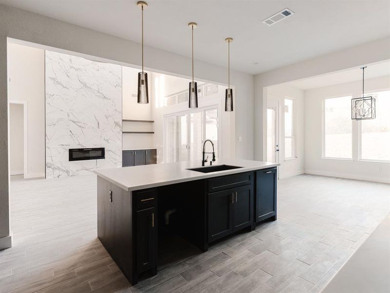 Kitchen featuring an island with sink, hanging light fixtures, sink, and light hardwood / wood-style floors