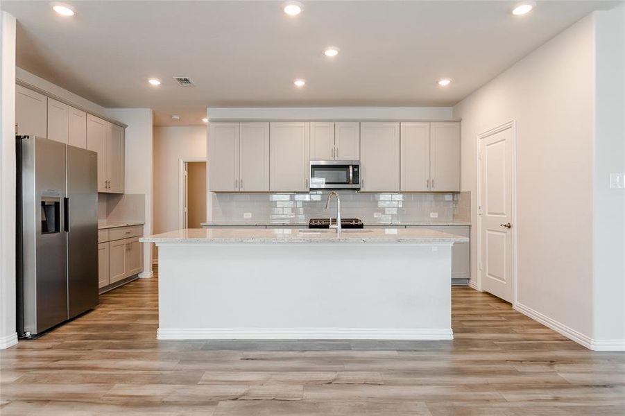 Kitchen with an island with sink, light wood-type flooring, and appliances with stainless steel finishes