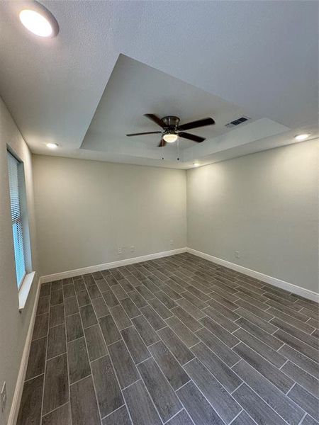 Spare room with a tray ceiling, ceiling fan, and dark hardwood / wood-style floors