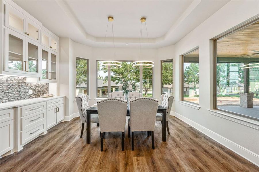 Dining room with an inviting chandelier, hardwood / wood-style flooring, and a raised ceiling