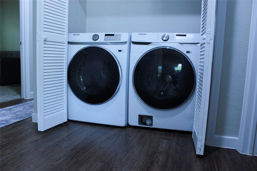 Laundry room featuring dark wood-type flooring and washing machine and clothes dryer