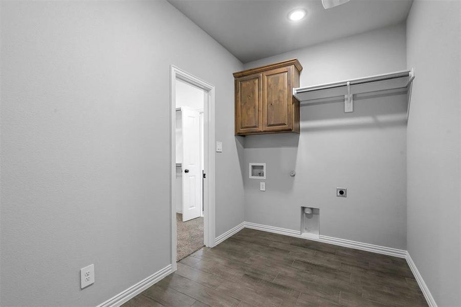 Laundry area featuring dark hardwood / wood-style flooring, cabinets, hookup for an electric dryer, hookup for a gas dryer, and washer hookup