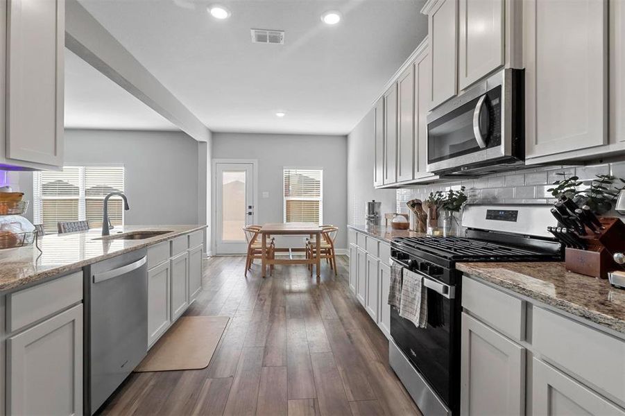 Kitchen featuring appliances with stainless steel finishes, white cabinets, sink, and dark hardwood / wood-style flooring