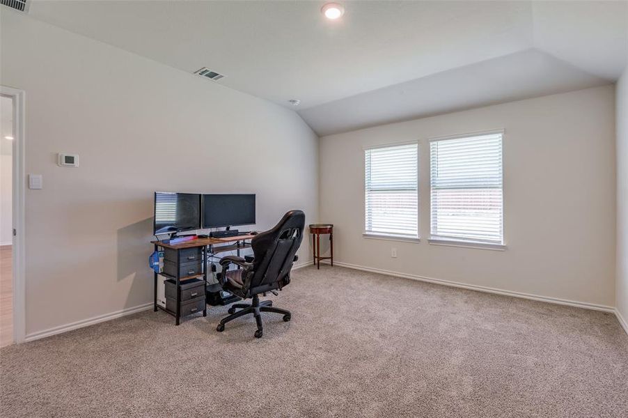 Carpeted office space featuring vaulted ceiling