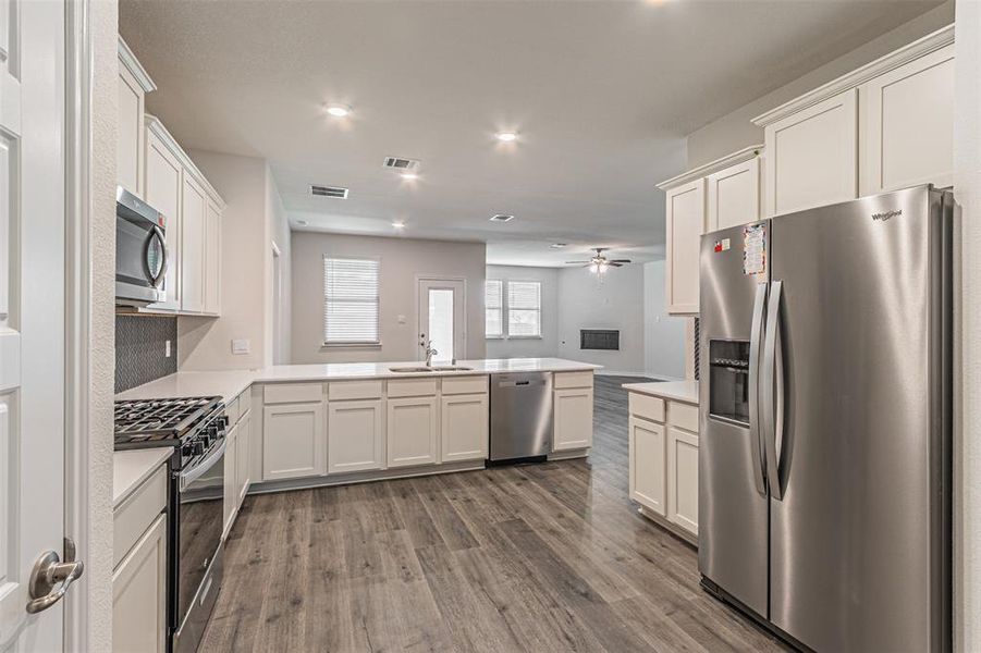 Kitchen featuring hardwood / wood-style flooring, ceiling fan, stainless steel appliances, sink, and kitchen peninsula
