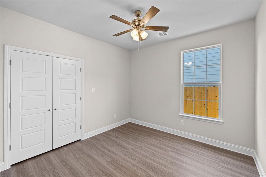 Unfurnished bedroom with ceiling fan, hardwood / wood-style floors, and a closet