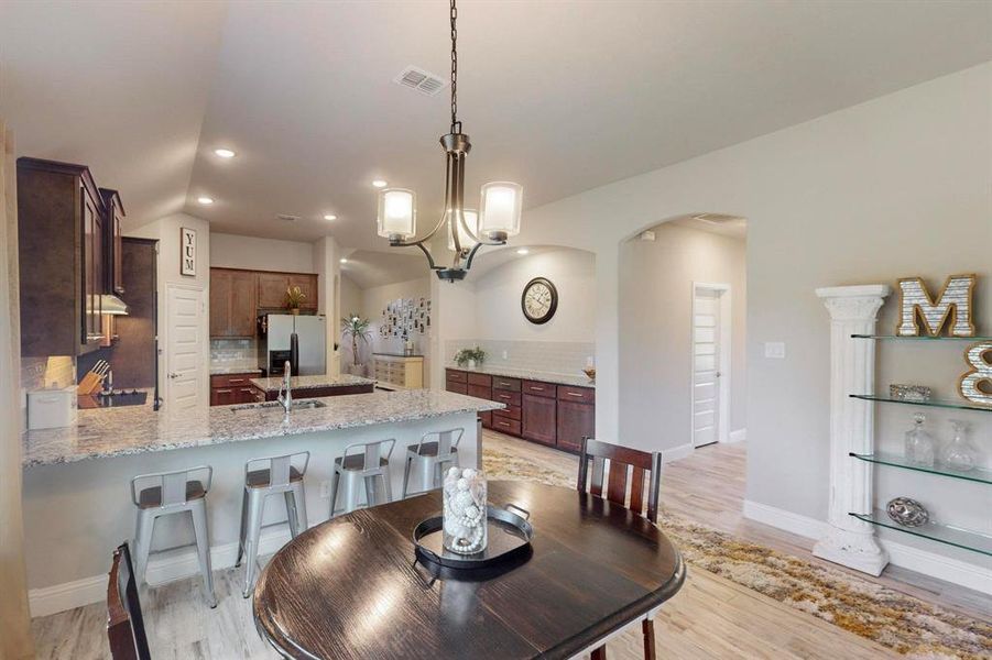 Dining area featuring vaulted ceiling, light hardwood / wood-style flooring, sink, and a chandelier