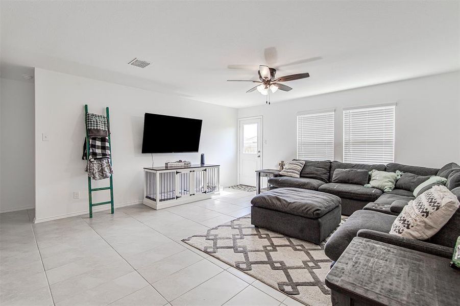 Living room featuring a wealth of natural light, light tile patterned floors, and ceiling fan