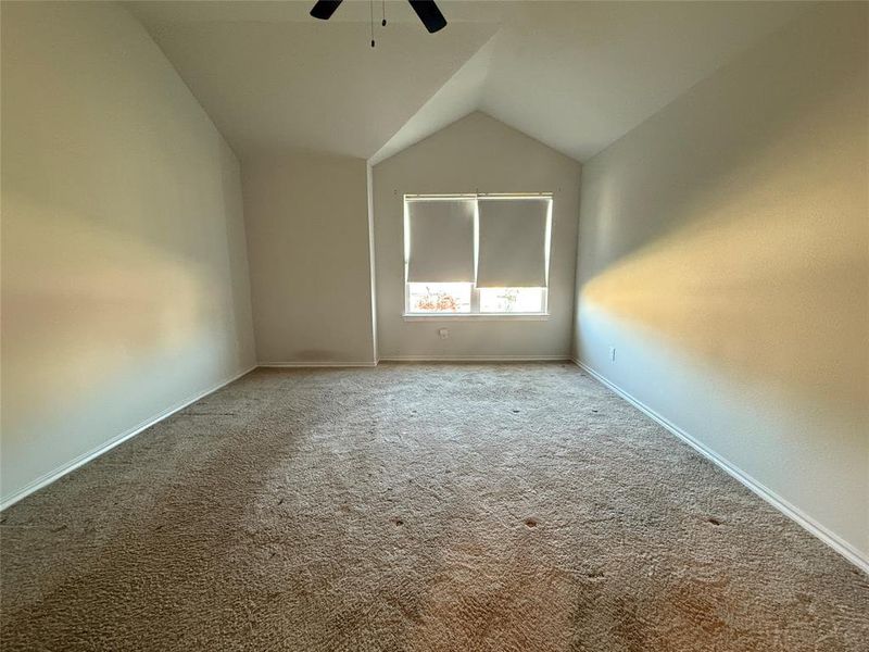 Spare room featuring ceiling fan, carpet floors, and vaulted ceiling