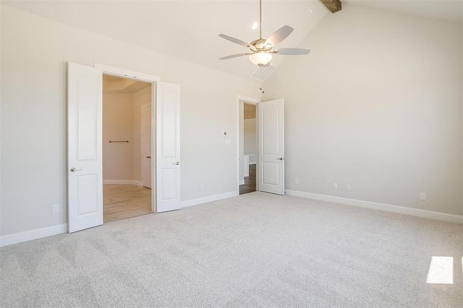 Unfurnished bedroom with beam ceiling, carpet, high vaulted ceiling, and ceiling fan