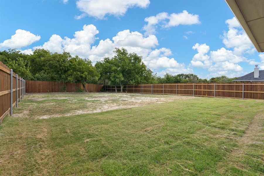 View of back yard with trees and privacy fence with steel posts